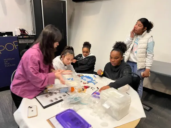 Youth gathered at a table working with beads and craft materials in a workshop