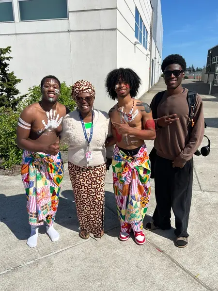 Youth in traditional African fabrics and body paint standing with a program leader outside