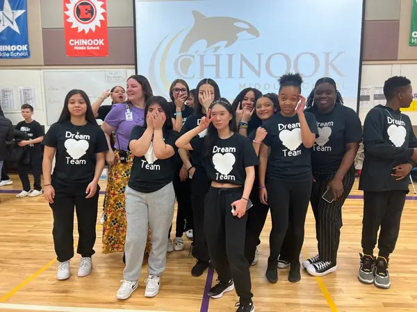 A group of students in Dream Team shirts posing inside a school gym